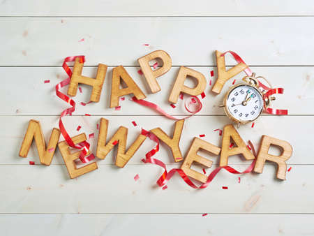 Happy New Year composition of the wooden letters surrounded with the multiple decorations over the white colored wooden boards surfaceの写真素材