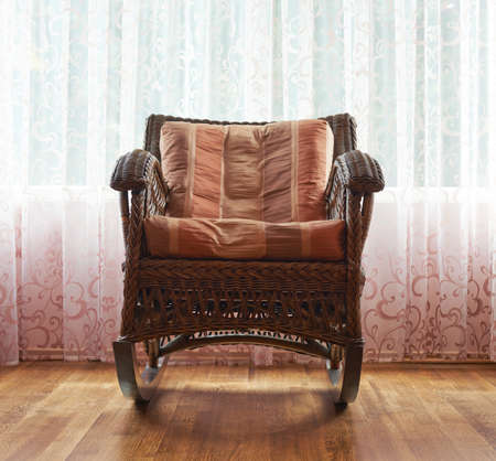 Brown wicker rocking chair against the windows curtains, indoor compositionの写真素材