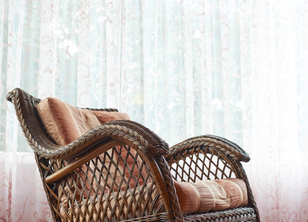 Brown wicker rocking chair against the windows curtains, indoor compositionの写真素材