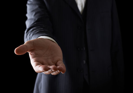 Giving a helping hand, asking or offering help close-up shot of a caucasian man in a business suit, low-key dramatic light compositionの写真素材