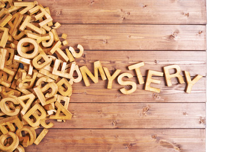 Word mystery made with block wooden letters next to a pile of other letters over the wooden board surface compositionの写真素材