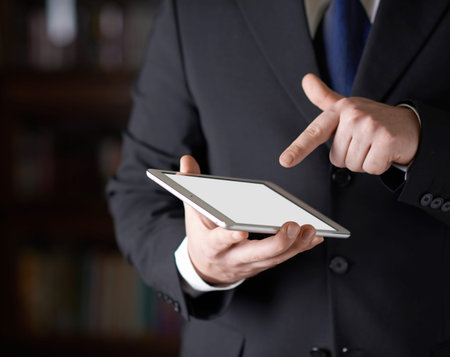 Close-up fragment of a man in a business suit holding a pad tablet in his hands, shallow depth of...