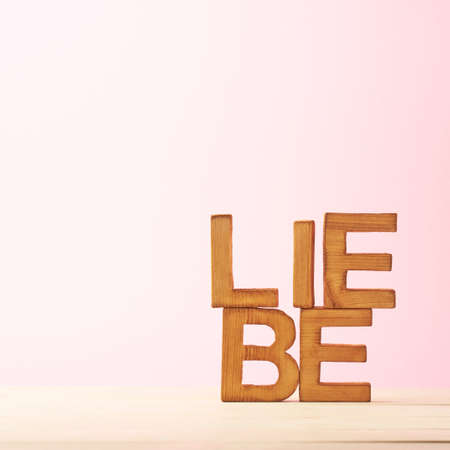 Word Liebe meaning Love in German language as a composition of wooden block letters against the pink backgroundの写真素材