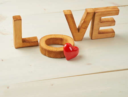 Word Love made with block letters over the wooden surface next to a single red heart as a Valentines Day love composition, backgroundの写真素材