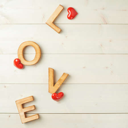 Word Love made with block letters over the wooden surface next to few glossy red hearts as a Valentines Day love composition, backgroundの写真素材