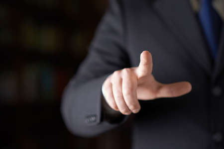 Close-up fragment of a man in a business suit holding a pointing finger in front of him, shallow depth of field compositionの写真素材