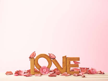 Love composition of wooden block letters covered with the dried flower potpourri agains the pink backgroundの写真素材
