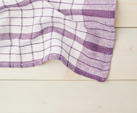 Violet squared tablecloth or towel over the surface of a wooden table