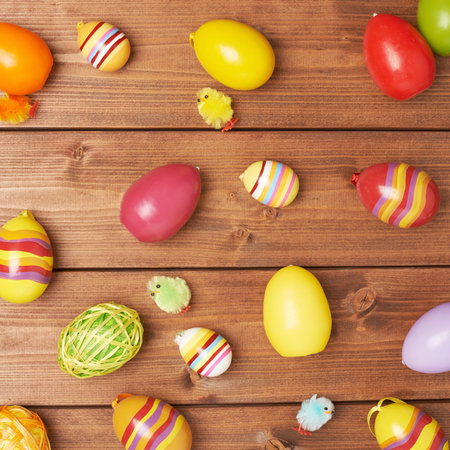 Multiple Easter egg decorations scattered over the brown wooden surface as a festive background...