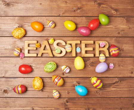 Word Easter made of wooden letters and surrounded with multiple egg decorations as a festive Easter...