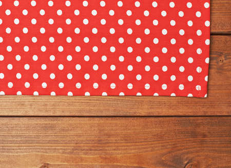 Red polka dot tablecloth or towel over the surface of a brown wooden tableの写真素材