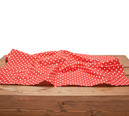 Red polka dot tablecloth or towel over the surface of a brown wooden table, composition isolated over the white backgroundの写真素材