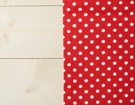 Red polka dot tablecloth or towel over the surface of a wooden table