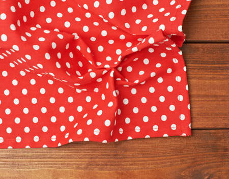 Red polka dot tablecloth or towel over the surface of a brown wooden tableの写真素材