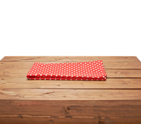 Red polka dot tablecloth or towel over the surface of a brown wooden table, composition isolated over the white backgroundの写真素材