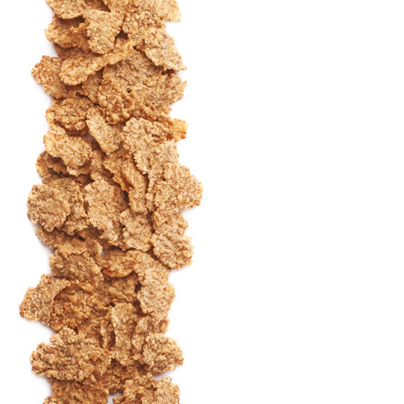 Whole grain cereal flakes aligned as a copyspace background composition isolated over the white...