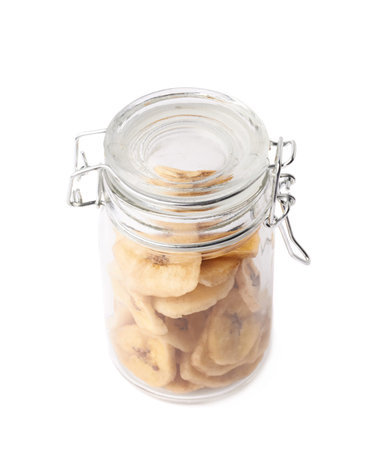 Glass jar filled with the dried banana snack slices, composition isolated over the white backgroundの写真素材