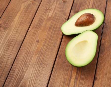 Avocado fruit lying over the brown colored wooden board surface as a background composition