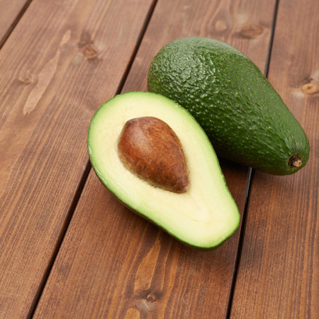 Avocado fruit lying over the brown colored wooden board surface as a background composition