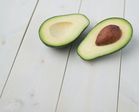 Avocado fruit lying over the white colored wooden board surface