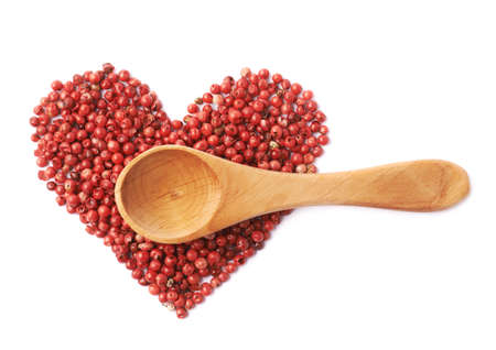 Woode spoon over the heart shape made of red pepper seeds isolated over the white backgroundの写真素材