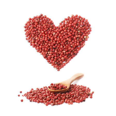 Wooden spoon over the pile of the red pepper seeds and heart shape over it, composition isolated over the white backgroundの写真素材