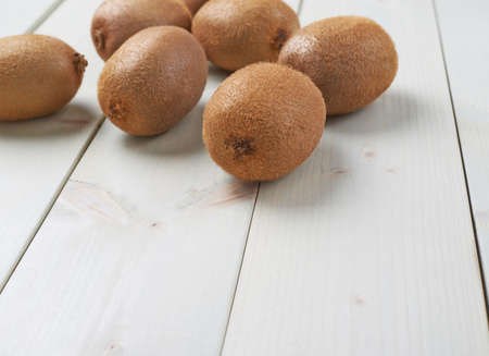Pile of multiple kiwifruits or chinese gooseberries over the white colored wooden boards surfaceの写真素材