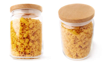 Set of glass jar filled with dry ditalini yellow pasta over isolated white background, different foreshorteningsの写真素材
