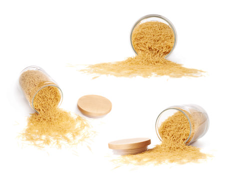 Set of glass jar filled with dry noodles yellow pasta over isolated white background, different foreshorteningsの写真素材