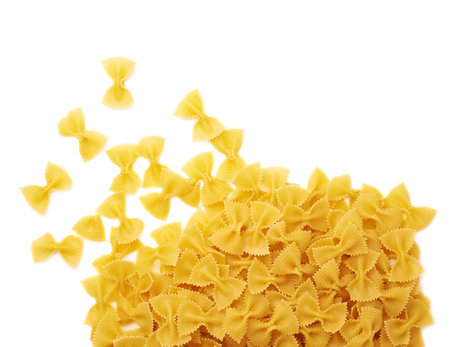 Pile of dry farfalle yellow pasta over isolated white background