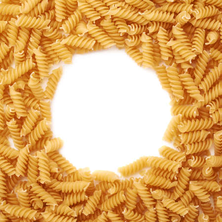 Round frame made of dry rotini yellow pasta over isolated white backgroundの写真素材