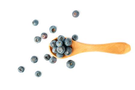 Wooden spoon filled of Ripe bilberry or blueberry over isolated white backgroundの写真素材