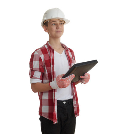 Cute teenager boy in red checkered shirt, building helmet and folder over white isolated background,...