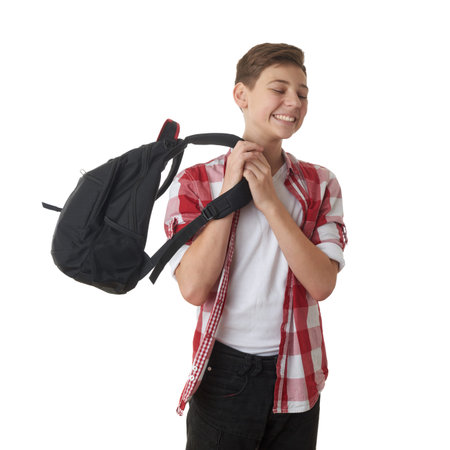 Cute teenager boy in red checkered shirt putting school bag on over white isolated background, half...