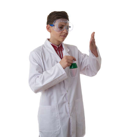 Cute teenager boy wearing white lab medic coat and protecting glasses with flask over white isolated background as science, experiment, healthcare conceptの写真素材