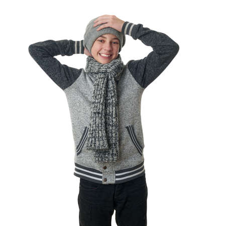 Cute teenager boy in gray sweater, hat and scarf with hands on head over white isolated background, half bodyの写真素材