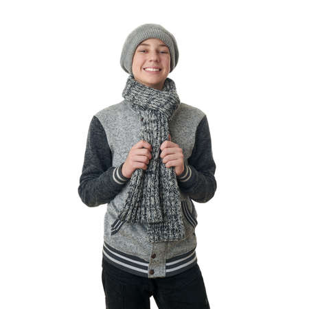Cute teenager boy in gray sweater, hat and scarf over white isolated background, half bodyの写真素材