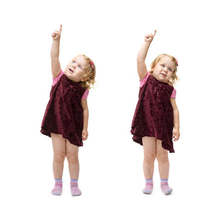 Young little girl with curly hair and pointing up copy space in purple dress standing over isolated white backgroundの写真素材