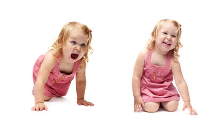 Young little girl with curly hair in pink dress crawling over isolated white backgroundの写真素材
