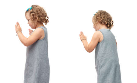 Young little girl with curly hair in gray dress standing and giving high five over isolated white backgroundの写真素材