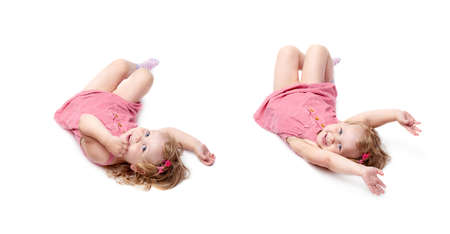 Young little girl with curly hair in pink dress lying over isolated white backgroundの写真素材