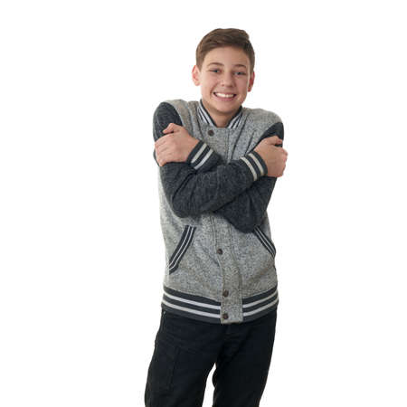 Cute teenager boy in gray sweater trying get warmer over white isolated background, half bodyの写真素材