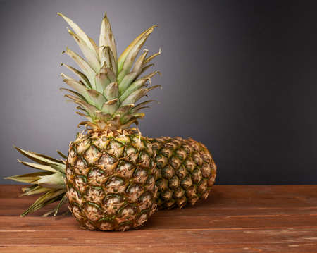 Raw whole pineapple on wooden brown surface tableの写真素材