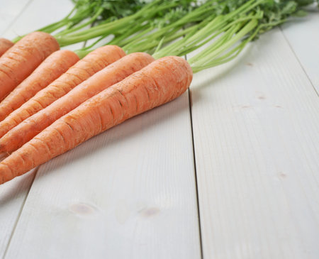 Bunch of raw whole carrots on white wooden surface tableの写真素材