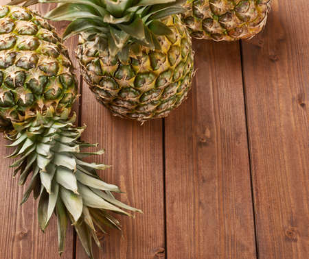 Raw whole pineapple on wooden brown surface tableの写真素材