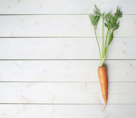 Raw whole carrot on white wooden surface tableの写真素材