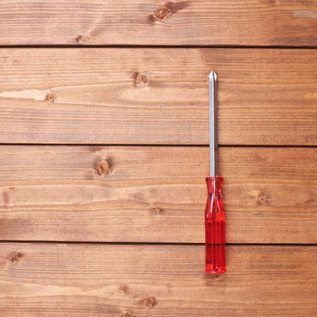 Cruciform screwdriver with the red handle on wooden brown surfaceの写真素材