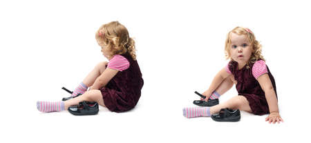 Young little girl with curly hair in purple dress sitting over isolated white backgroundの写真素材