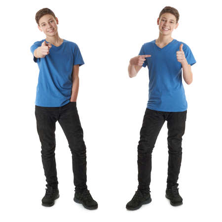 Cute teenager boy in blue T-shirt standing and poinitng forward over white isolated background full bodyの写真素材