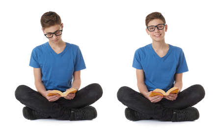 Cute teenager boy with book in blue T-shirt, glasses and lotus posture over white isolated backgroundの写真素材